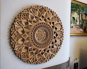May include: A large, intricately carved wooden mandala wall hanging with a brown wood finish. The mandala features a circular design with multiple layers of intricate patterns.