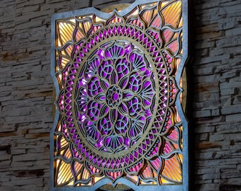 Può includere: Un decoro da parete quadrato in legno con un design a mandala viola e oro. Il mandala è finemente intagliato e ha un effetto 3D. Il decoro è illuminato da dietro, creando un bagliore caldo.