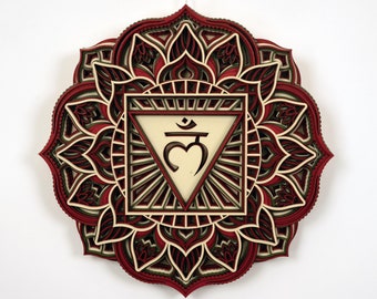 May include: A red, green, and cream colored wooden mandala with a layered design. The center of the mandala features a white triangle with a heart and the symbol "Svadhisthana" in Sanskrit.
