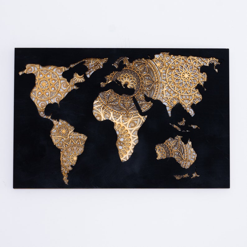 Puede incluir: Un mapa del mundo de madera negra con un dise&ntilde;o de mandala dorado recortado. El mapa es una decoraci&oacute;n de pared.