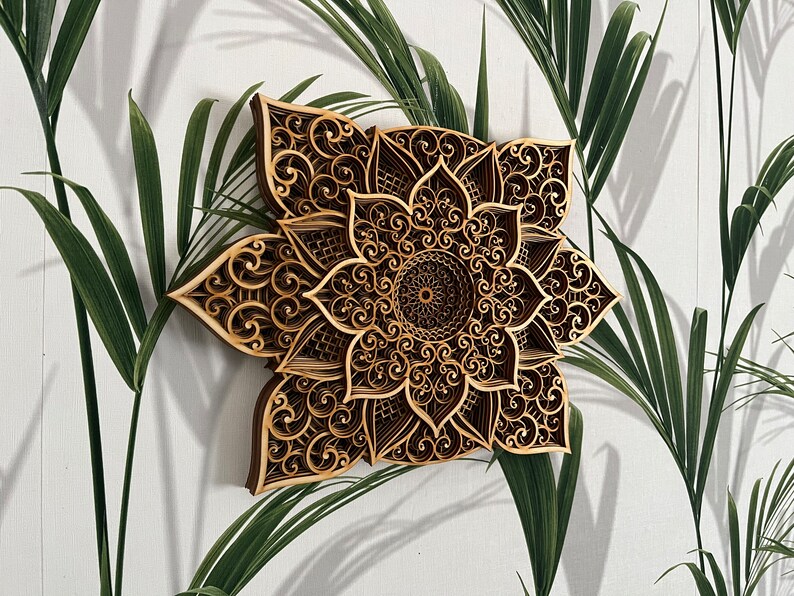 May include: A brown wooden mandala wall decor with intricate laser cut designs. The mandala features a circular pattern with a flower-like shape.