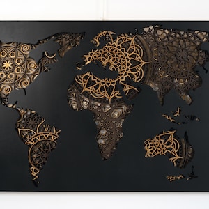 Puede incluir: Una pieza de arte de pared negra que presenta un mapa del mundo con intrincados dise&ntilde;os de mandala recortados en tonos dorados y marrones.
