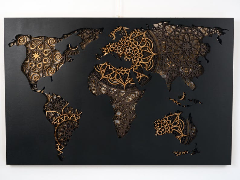 Puede incluir: Una pieza de arte de pared negra que presenta un mapa del mundo con intrincados dise&ntilde;os de mandala recortados en tonos dorados y marrones.
