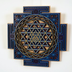 May include: A blue and gold Sri Yantra mandala wall art made of wood. The intricate design features a geometric pattern with multiple layers.