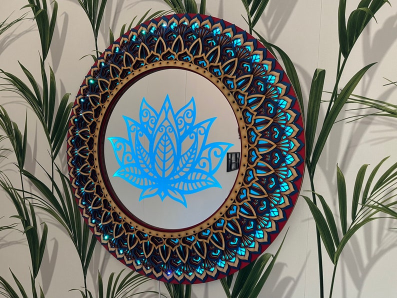 May include: A round wooden mirror with a blue and gold mandala design. The mirror has a blue lotus flower design in the center.