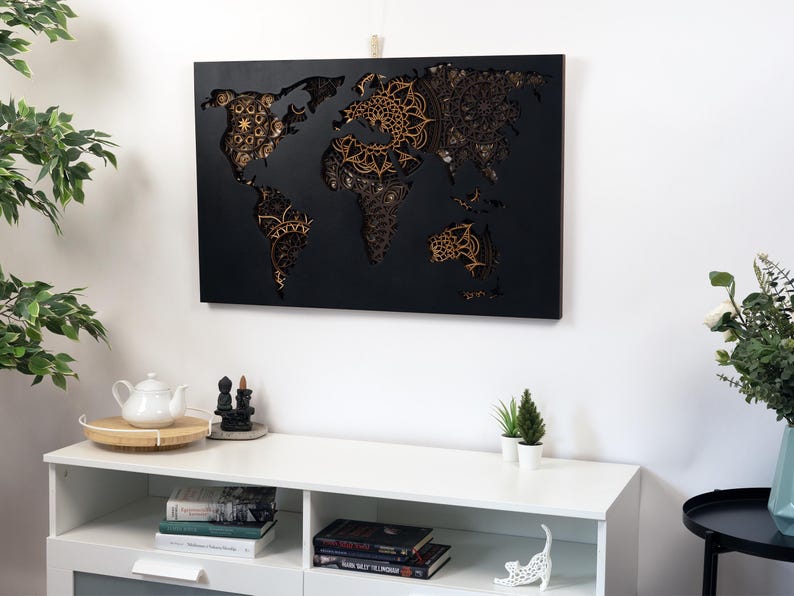 Puede incluir: Una decoraci&oacute;n de pared de mapa del mundo de madera negra con intrincados dise&ntilde;os de mandala recortados en color dorado.