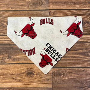 May include: White dog bandana with a red Chicago Bulls logo and the text "Chicago Bulls" and "Bulls".