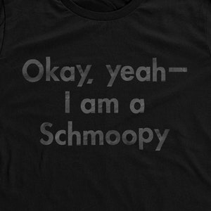 May include: Black t-shirt with the text "Okay, yeah - I am a Schmoopy" printed on the front.
