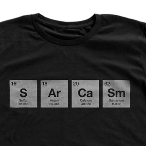 Könnte beinhalten: Schwarzes T-Shirt mit einer weißen Grafik von vier Elementen aus dem Periodensystem: Schwefel (S), Argon (Ar), Calcium (Ca) und Samarium (Sm).