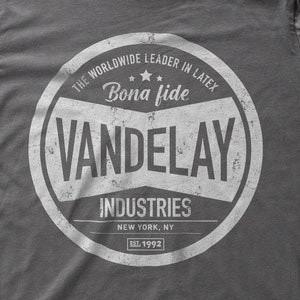 Könnte beinhalten: Ein graues T-Shirt mit einem weißen kreisförmigen Logo, auf dem "The Worldwide Leader in Latex", "Bona fide", "Vandelay Industries", "New York, NY" und "Est. 1992" steht.