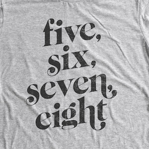 Pode incluir: Uma camiseta cinza mescla com o texto "five, six, seven, eight" impresso em preto.