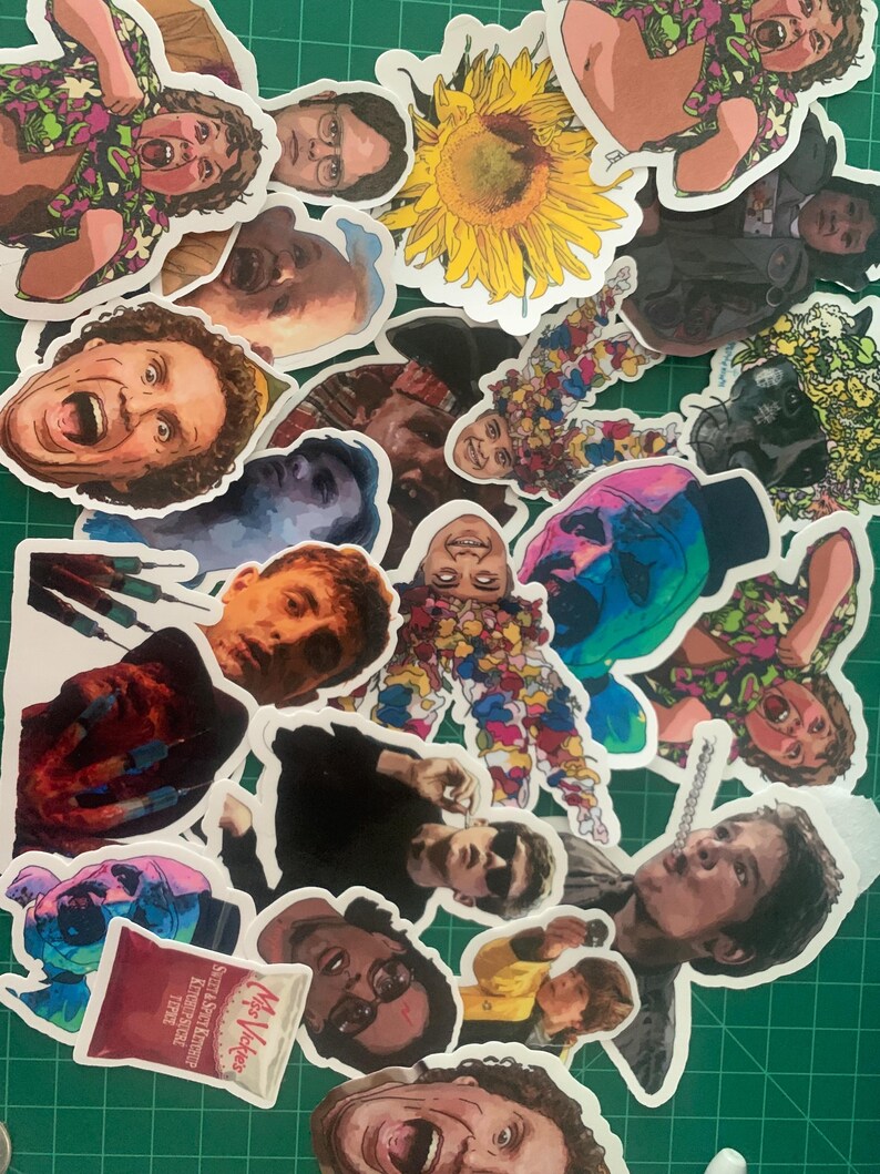 May include: A collection of colorful stickers featuring various characters and images, including a sunflower, a person with a red shirt, and a person with a blue shirt. The stickers are printed on white paper and have a glossy finish.