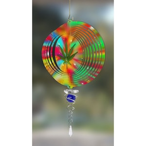 May include: A colorful, tie-dye wind spinner with a green marijuana leaf design. The spinner has a blue glass bead and a crystal hanging from the bottom.