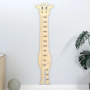 May include: A light-colored wooden giraffe-shaped growth chart featuring a vertical scale from 50 to 180 centimeters. The giraffe head is at the top, and the body is constructed from several interlocking puzzle-like pieces with black markings.