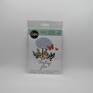May include: A pack of 12 metal dies for crafting. The dies feature a tree with leaves, flowers, butterflies, and the words "Thinking of you".