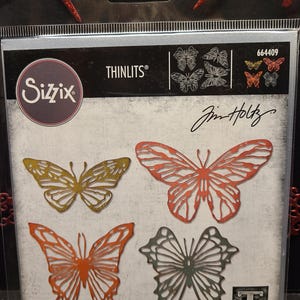 Könnte beinhalten: Eine Packung mit vier Sizzix Thinlits-Stanzformen mit Schmetterlingsmotiven von Jim Holtz. Die Stanzformen sind aus Metall und für die Verwendung mit einer Stanzmaschine konzipiert. Die Packung enthält vier Stanzformen, vier Matrizen, vier Troqueles, vier Fustelle, vier вырубки, vier Stanzen und vier Cortantes.