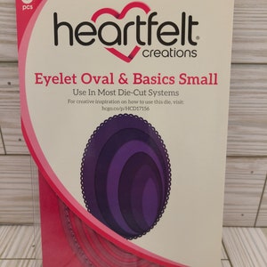 Puede incluir: Un paquete de seis troqueles de artesanía Heartfelt Creations para usar en la mayoría de los sistemas de troquelado. El paquete muestra un troquel ovalado de ojal morado con un borde festoneado. El texto del paquete dice "Eyelet Oval & Basics Small" y "HCD1-7156".