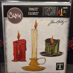 Puede incluir: Un conjunto de 23 formas de velas troqueladas para manualidades. El conjunto incluye tres diseños de velas diferentes: una vela roja, una vela blanca con una base dorada y una vela verde. Los troqueles están diseñados por Jim Holtz y forman parte de la colección Sizzix Thinlits Colorize.