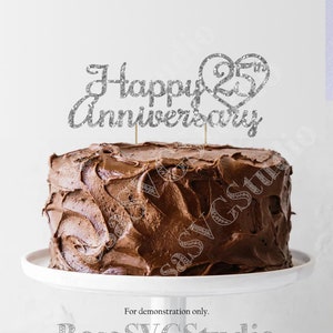 May include: Silver glitter cake topper with the text "Happy 25th Anniversary" and a heart with the number 25 inside. The topper is on top of a chocolate cake.