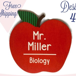 May include: Red apple-shaped wooden teacher name tag with a green leaf. The tag says "Mr. Miller" and "Biology" in white text.