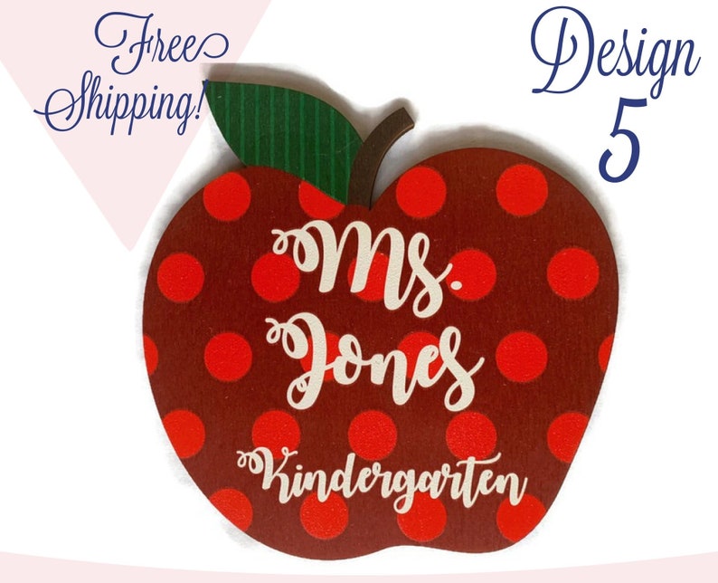 May include: Red apple-shaped wooden sign with white polka dots. The sign says "Ms. Jones Kindergarten" in white lettering.