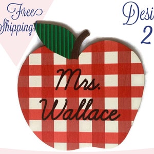 May include: Red and white checkered apple-shaped wooden sign with the text "Mrs. Wallace" in black cursive lettering.
