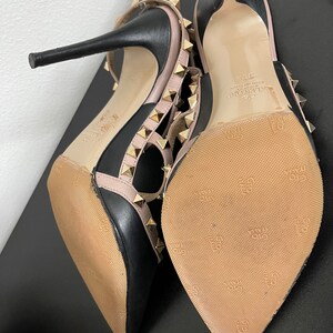 May include: Black and pink leather high heel shoes with gold studs and a Valentino logo on the sole.