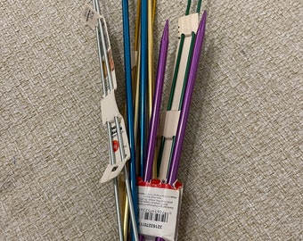 May include: A bundle of colorful knitting needles in various sizes, including silver, gold, blue, purple, and green. The needles are bundled together with a rubber band and have a price tag attached.