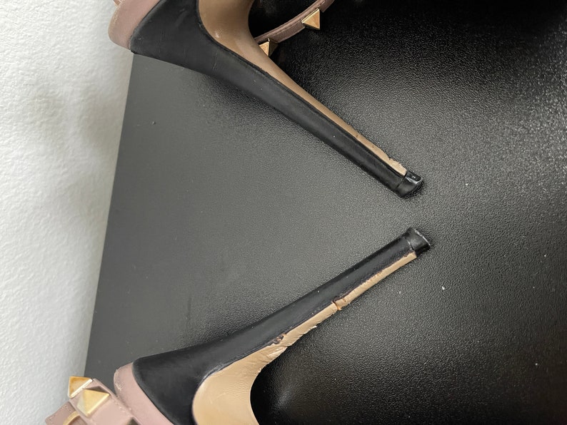 May include: A pair of black high heel shoes with gold studs. The shoes are broken and the heels are separated from the rest of the shoe.