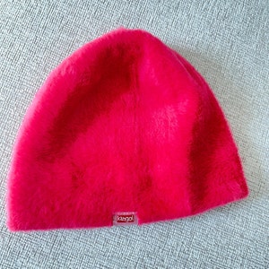 May include: A bright pink faux fur beanie with a small "Kangol" logo label.
