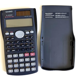 May include: A dark blue Casio fx-300MS scientific calculator with its protective cover open. The calculator has numerous buttons for various mathematical functions, a display screen, and a solar panel. The cover displays instructions.