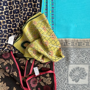 May include: Four different patterned fabric squares, one with a floral design, one with a geometric design, one with a yellow and pink design, and one with a blue and white design. The floral square has a pink tag with the word "LOFT" on it.