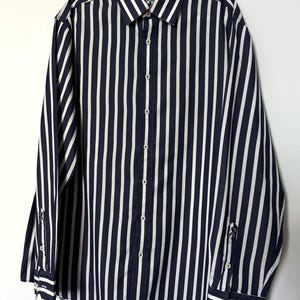 May include: A long-sleeved shirt with vertical navy blue and white stripes. The shirt has a button-down front, a collared neckline, and buttoned cuffs. The shirt is hanging on a hanger against a white background.