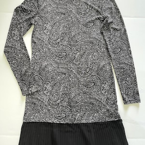 May include: Black and white paisley print long-sleeved dress with a black pleated chiffon bottom.