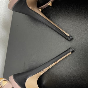 May include: A pair of black high heel shoes with gold studs. The shoes are broken and the heels are separated from the soles.