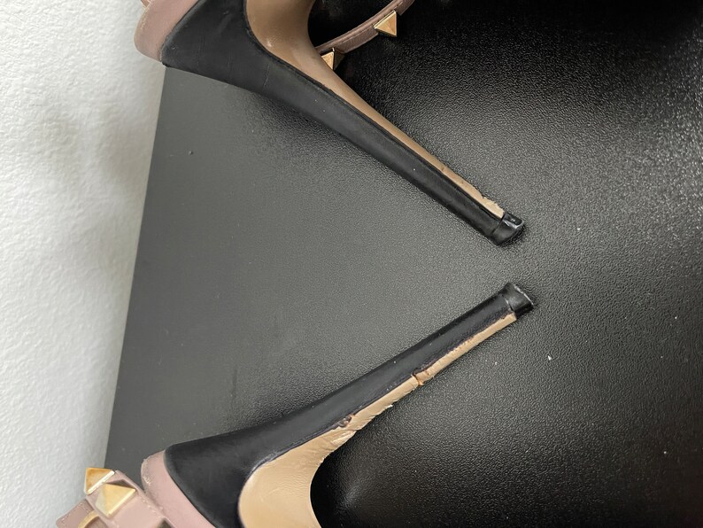 May include: A pair of black high heel shoes with gold studs. The shoes are broken and the heels are separated from the soles.
