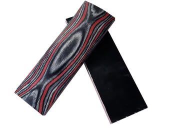 May include: Two rectangular wood pieces. One features a striking pattern of red and gray streaks over a black base. The other is solid black. These pieces could be used for crafting or woodworking projects.