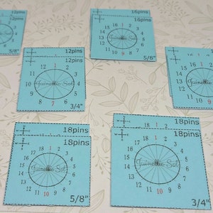 Op de afbeelding: Een set van zes blauwe en witte ronde kunststof gradenboog met zwarte markeringen en een rood "Juinelle Sol" logo. De gradenbogen zijn gelabeld met het aantal pinnen, de diameter in inches en de nummers 1 tot en met 18.