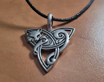 May include: Silver-toned pendant featuring a stylized fox head within a Celtic knot design. The pendant hangs from a black cord. The intricate details of the fox and knotwork are visible. The pendant is likely made of metal.