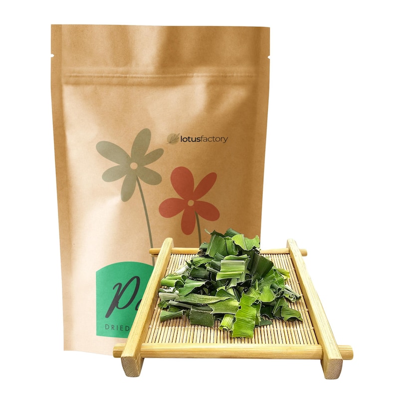 Cut dried green pandan leaves piled on a mini wooden bamboo tray. Displayed in front of a stand-up kraft paper zipper pouch for lotusfactory, ideal for natural botanicals, potpourri, crafts, and aromatic supplies.