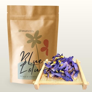 May include: A brown paper pouch labeled lotusfactory Blue Lotus Petals & Stamen with a floral graphic, positioned next to a small bamboo tray holding a pile of dried, vibrant blue and yellow lotus petals and stamen for botanical use.