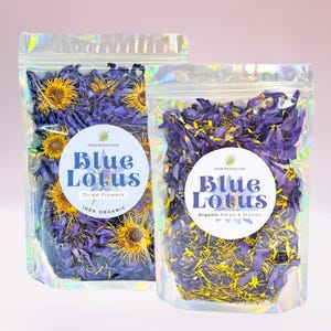 May include: Two resealable bags of dried blue lotus flowers. The bag on the left contains whole flowers, while the bag on the right contains petals and stamen. Both bags have labels that say "Blue Lotus" and "lotus-factory.com". The bag on the left also says "Dried Flowers" and "100% Organic". The bag on the right says "Organic Petals & Stamen".