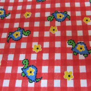 Puede incluir: Tela con un estampado de cuadros rojos y blancos. La tela está decorada con tortugas azules con centros de flores amarillas y flores amarillas. Las tortugas tienen cabezas y colas verdes. La tela es probablemente de algodón.
