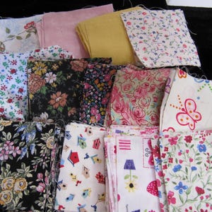 May include: A collection of square fabric swatches featuring various patterns including floral prints, butterflies, birdhouses, and solid colors in shades of pink, yellow, black, and white with frayed edges stacked in a pile.