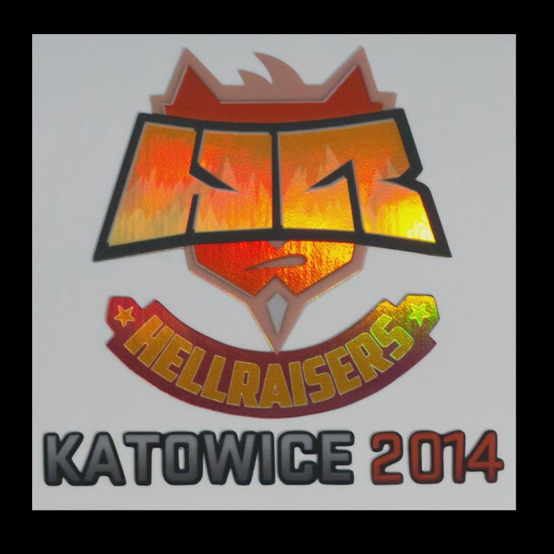 May include: A holographic sticker featuring the HellRaisers team logo with a stylized HR monogram above a banner reading HELLRAISERS and the text KATOWICE 2014 below. The design uses orange, red, and yellow metallic gradients with black outlines.