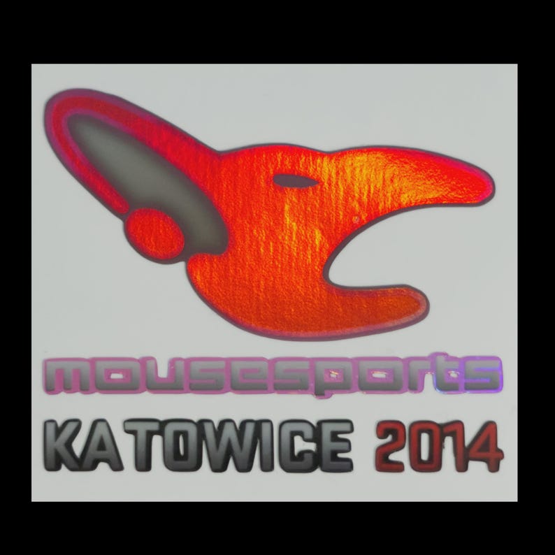 May include: A sticker featuring a stylized red and orange mouse head logo above the text mousesports in purple and the text KATOWICE 2014 in black and red. The design has a metallic, reflective finish on a light gray background with a black border.