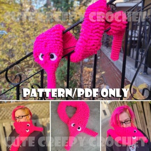 Puede incluir: Un patrón de crochet para una bufanda de gusano rosa. El patrón está disponible para descargar en PDF. La imagen muestra la bufanda puesta por una persona y también como elemento decorativo.