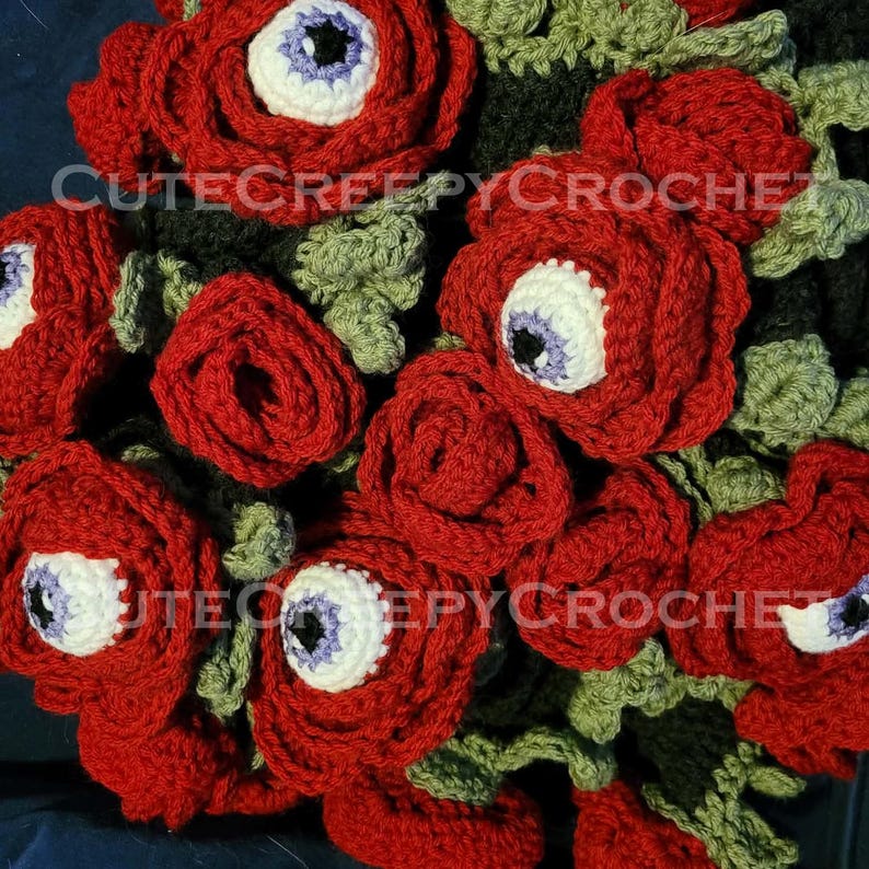 May include: A crocheted bouquet of red roses with white and purple eye centers. The green leaves and dark background create a striking contrast. The text "CUTECREEPYCROCHET" is visible on the image. This unique handmade item is perfect for Halloween or gothic decor.