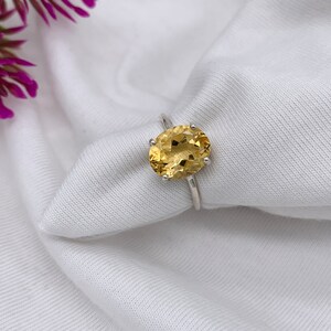 May include: A silver ring with a large oval-shaped topaz gemstone. The gemstone is a light yellow color.