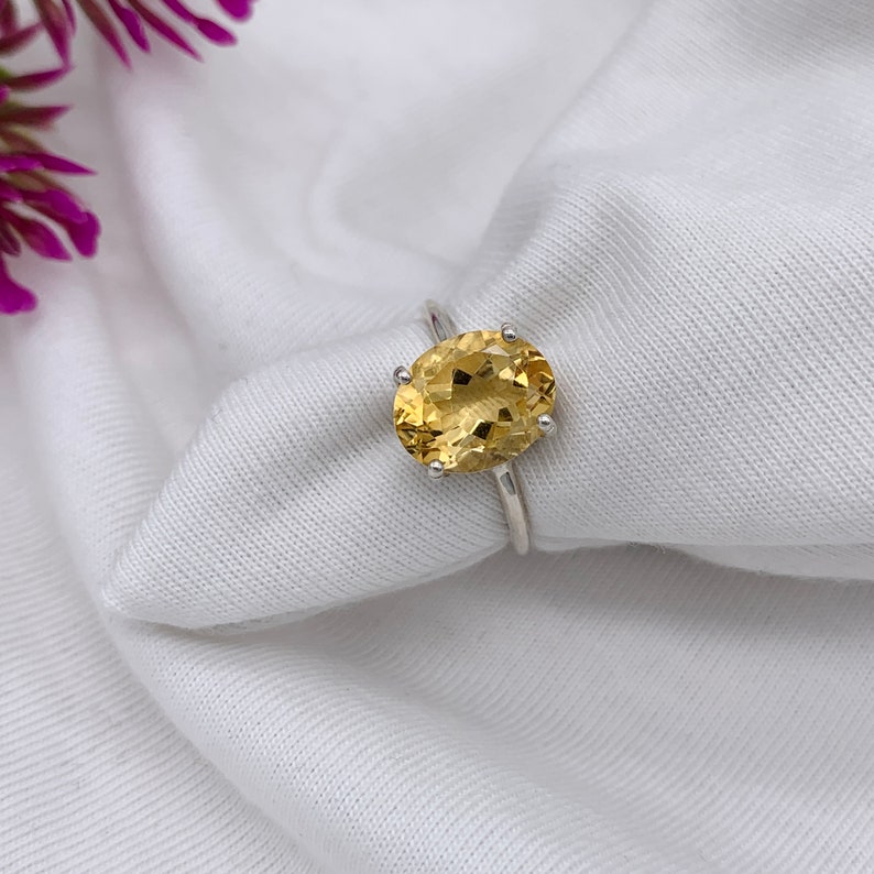 May include: A silver ring with a large oval-shaped topaz gemstone. The gemstone is a light yellow color.